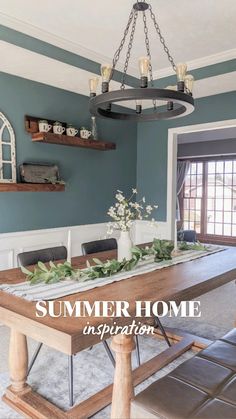 a dining room table with candles and greenery on it, in front of a blue wall