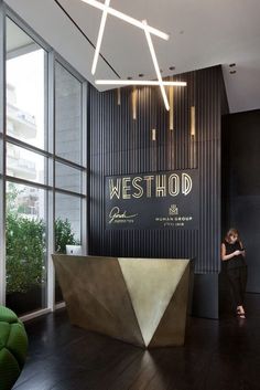 a woman is standing in front of the westhod sign on the wall behind her