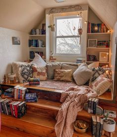 a window seat in the corner of a room with lots of books and pillows on it