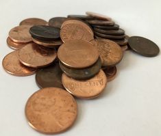 a pile of coins sitting on top of a white table next to another pile of pennets