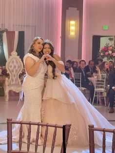 two women in wedding gowns taking pictures with their cell phones on the dance floor