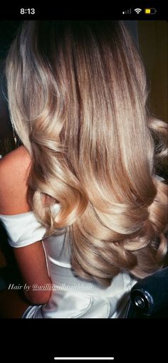 the back of a woman's head with long, blonde hair and wavy curls