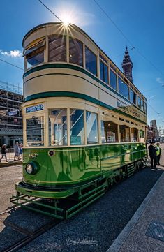 a green and white trolley car sitting on the tracks