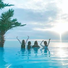 three women in the pool waving at the sun