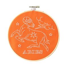 an orange embroidered hoop with the words aries on it and a horse running through stars