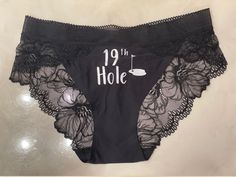 the panties are black and have white writing on them that says 19 th hole with an image of a golf course