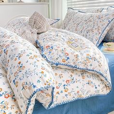 a bed with blue and white comforter, pillows and pillow cases on top of it