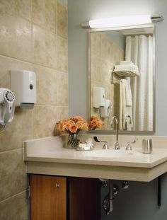 a bathroom sink sitting under a mirror next to a towel dispenser