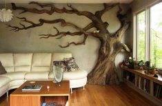 a living room with white furniture and a tree mural on the wall