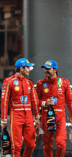 two men in red racing suits standing next to each other