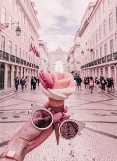 a person holding up an ice cream cone with pink frosting