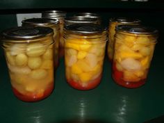 four jars filled with pickled fruit sitting on top of a table