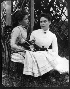 two women sitting next to each other in the grass