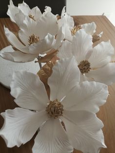 some white flowers are sitting on a wooden table and ready to be placed in the vase