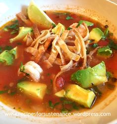 a bowl of soup with shrimp, avocado, and tortilla strips