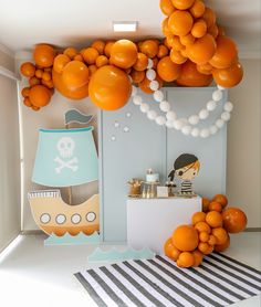 an orange themed birthday party with balloons and decorations on the wall, including a pirate ship