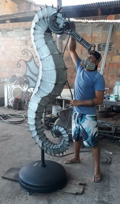 a man standing next to a large metal seahorse sculpture on top of a table