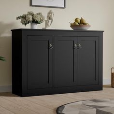 a black cabinet sitting on top of a hard wood floor next to a potted plant