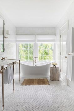 a bathroom with a large white bathtub next to a window