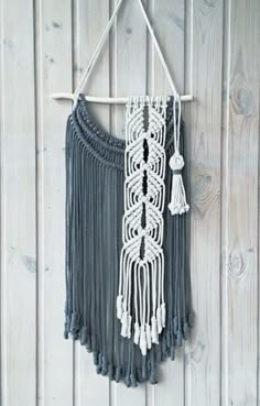 a macrame with tassels hanging on a white wooden wall in front of a wood paneled wall