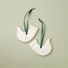 two white ceramic birds hanging from green ribbon