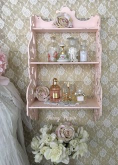 a pink shelf with flowers and perfume bottles on it