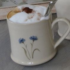 two mugs with spoons in them sitting on a table