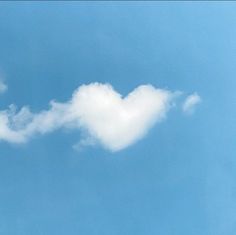 an airplane flying in the sky with a cloud shaped like a heart on it's tail