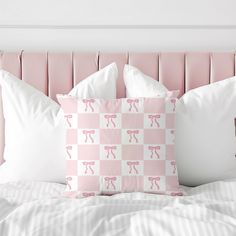 a pink and white bed topped with two pillows next to a headboard covered in sheets