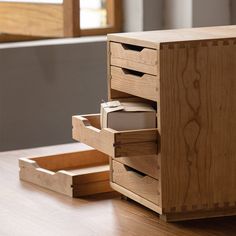 a wooden desk with drawers on the bottom and one drawer open to show items inside