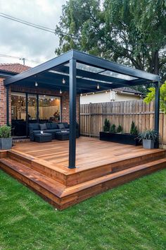 a wooden deck in the middle of a yard with an attached gazebo and seating area