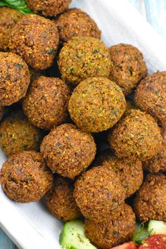 a white bowl filled with meatballs and vegetables on top of a blue table cloth