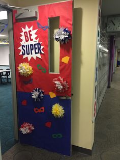 a door decorated with paper flowers and streamers in an office cubicle area that says be super