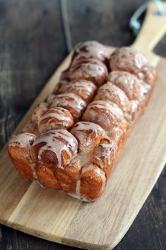 a wooden cutting board topped with donuts covered in icing