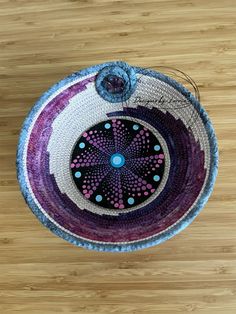 a purple and white bowl sitting on top of a wooden floor