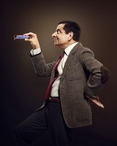 a man in a suit and tie is holding a candy bar