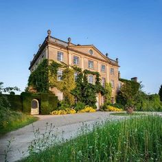 an old building with vines growing on it's side and flowers in the foreground