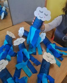 a child is holding up some blue paper rolls with clouds on them and one has eyes closed