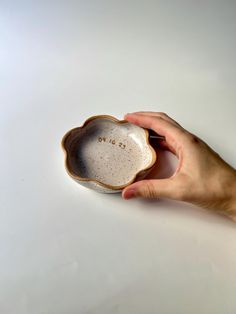 a hand holding a small white bowl with the word love on it's side