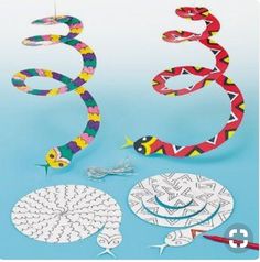 the paper snake is next to some scissors and other crafting supplies on a blue background