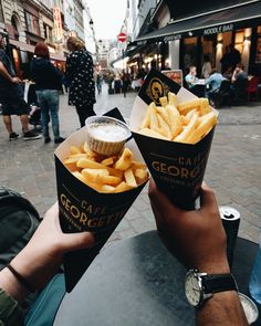 two people are holding up their food in front of each other on the street corner