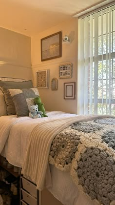 a bedroom with a bed, window and stuffed animal on the bottom shelf next to it