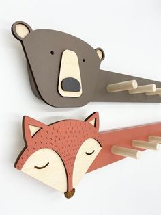 there are two wooden animals on the wall next to each other, one is a fox and the other has a bear's head