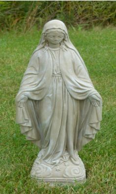 a statue of the virgin mary is sitting in the grass