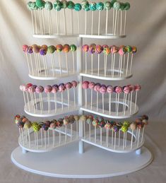 a white cake stand filled with lots of colorful candies on top of each other