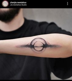 a man's arm with a black and white circle tattoo on the left forearm