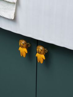 there are two yellow turtle knobs on the side of a green cabinet door that is closed