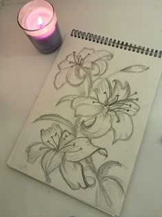 a pencil drawing of flowers next to a lit candle on a white paper with black ink