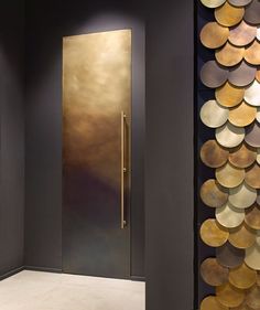 a modern entry way with gold and silver discs on the wall, along with a large door