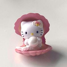 a hello kitty figurine sitting on top of a pink bowl with a flower in it